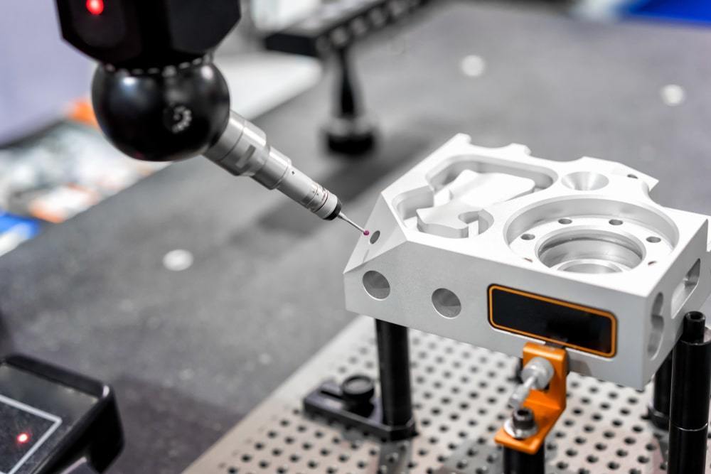 A Coordinate Measuring Machine (CMM) uses a contact probe to check the dimensions of a machined part.